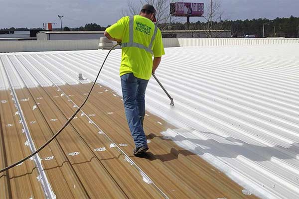 Roofing professional applying a silicone coating to a metal roof for waterproofing and UV protection. Durable, energy-efficient solution for roof restoration.